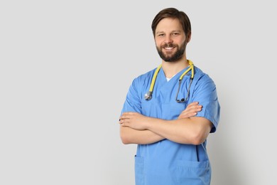 Doctor or medical assistant (male nurse) with stethoscope on light grey background. Space for text