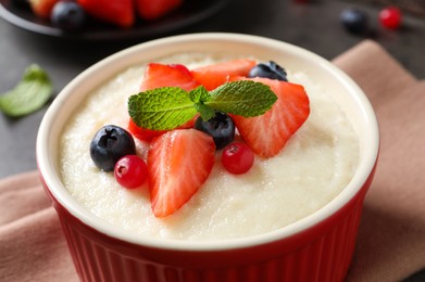 Photo of Delicious semolina pudding with berries and mint on table, closeup