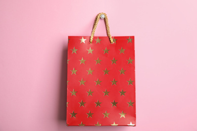 Photo of Red shopping paper bag with star pattern on pink background