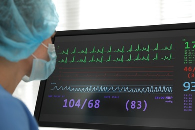 Nurse near monitor with cardiogram in hospital