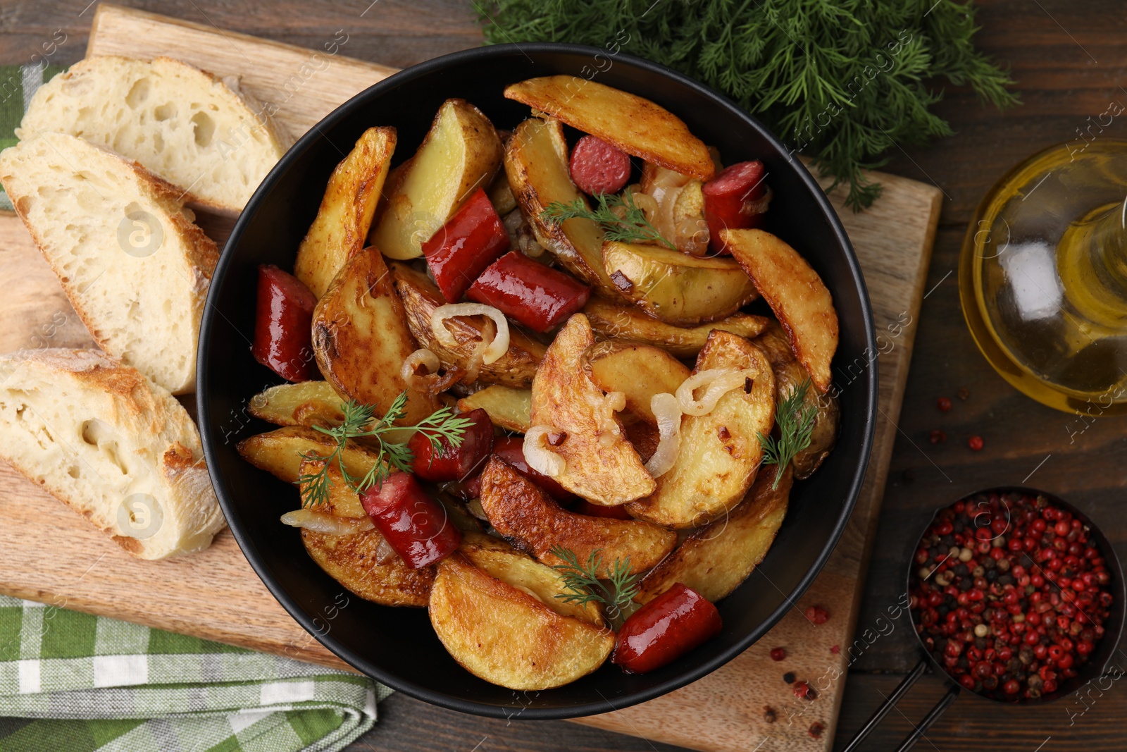 Photo of Delicious baked potato with thin dry smoked sausages in bowl, bread and spices on wooden table, flat lay