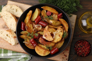 Photo of Delicious baked potato with thin dry smoked sausages in bowl, bread and spices on wooden table, flat lay