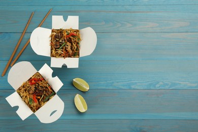 Photo of Boxes of wok noodles with vegetables, meat and chopsticks on light blue wooden table, flat lay. Space for text