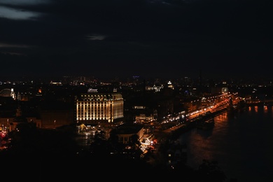Photo of KYIV, UKRAINE - MAY 21, 2019: Beautiful view of night cityscape with illuminated buildings near river