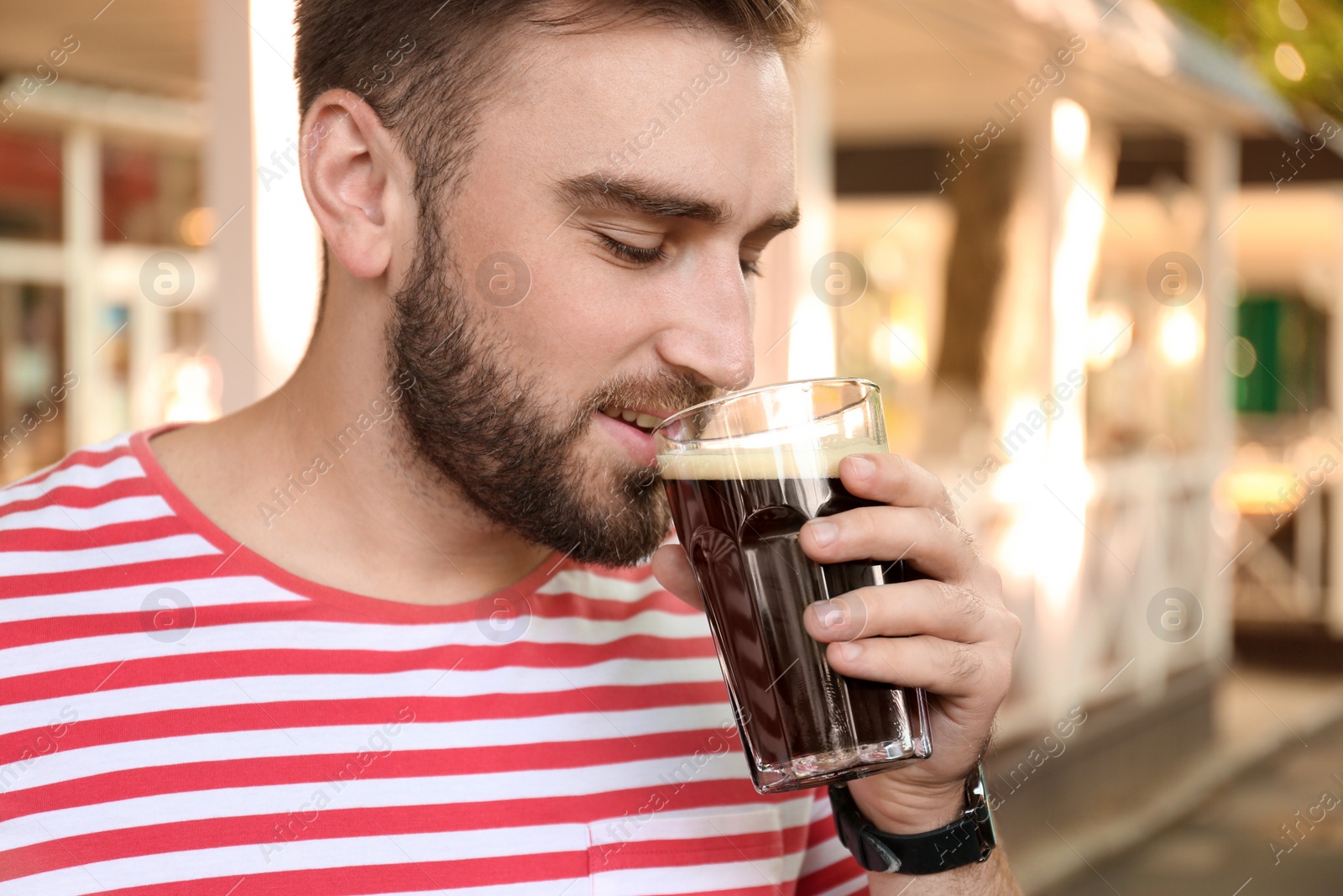 Photo of Handsome man with cold kvass outdoors. Traditional Russian summer drink