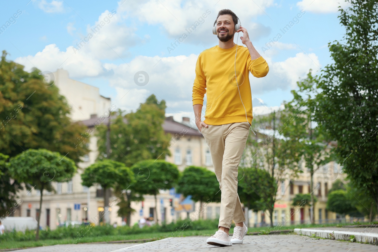 Photo of Handsome man with headphones walking on city street