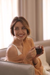 Beautiful young woman with cup of tea relaxing at home. Cozy atmosphere