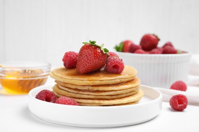 Photo of Tasty pancakes with fresh berries and honey on white table