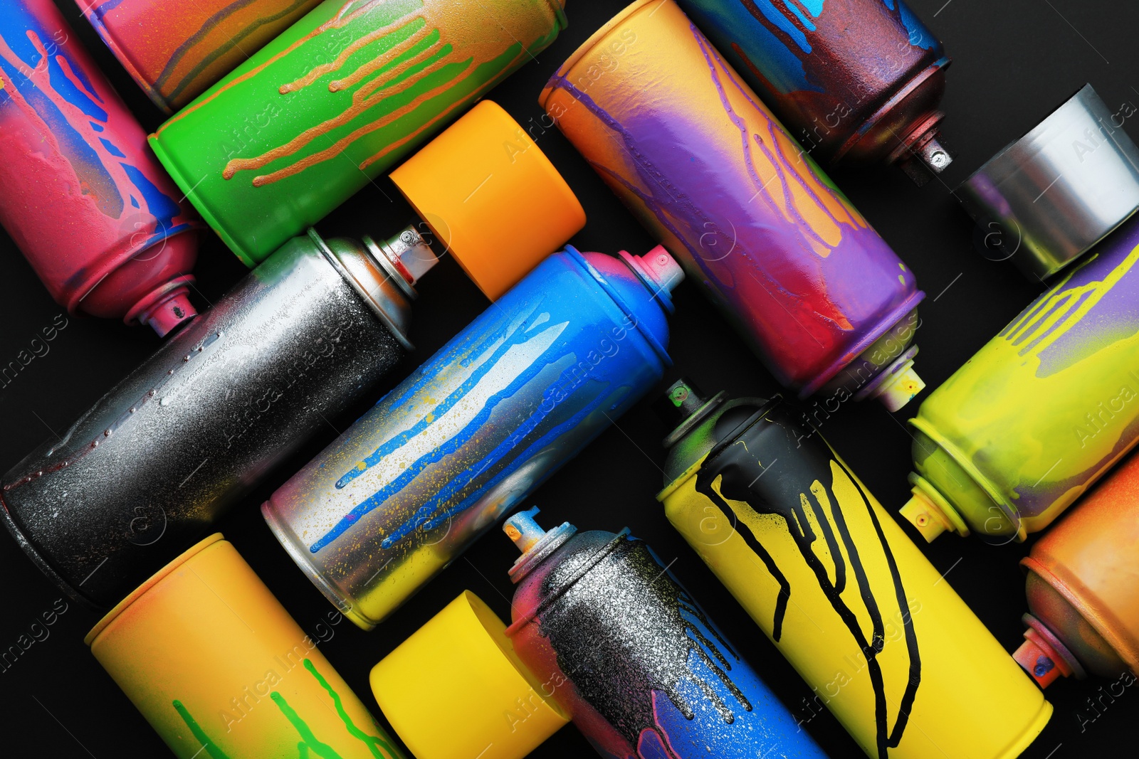 Photo of Used cans of spray paints on black background, flat lay. Graffiti supplies