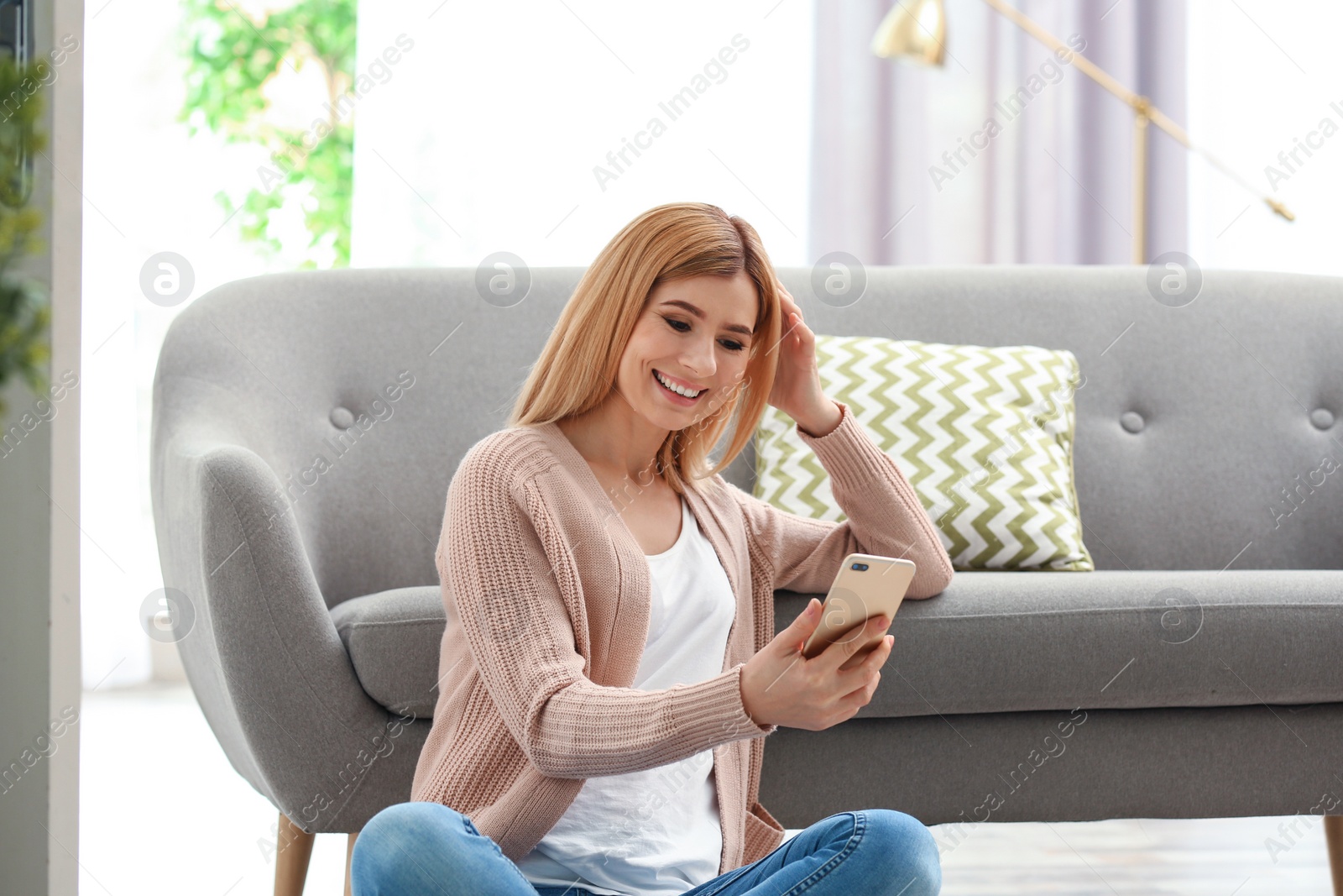 Photo of Woman using mobile phone for video chat in living room