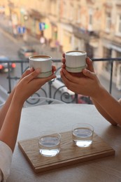 Friends drinking coffee at wooden table in cafe, closeup