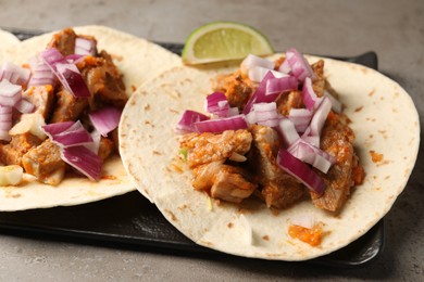 Photo of Delicious tacos with vegetables and meat on grey textured table, closeup