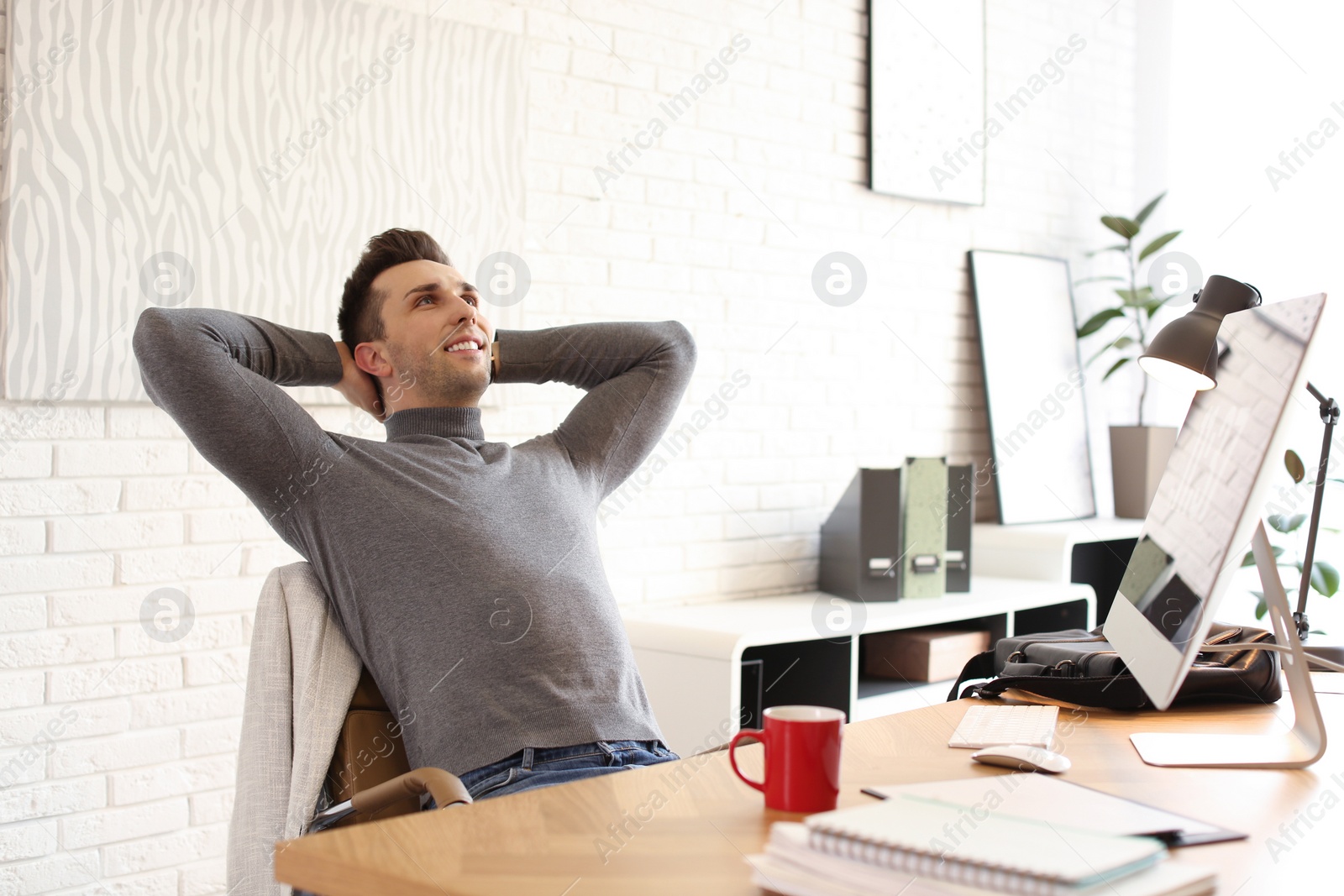 Photo of Young man relaxing at table in office during break