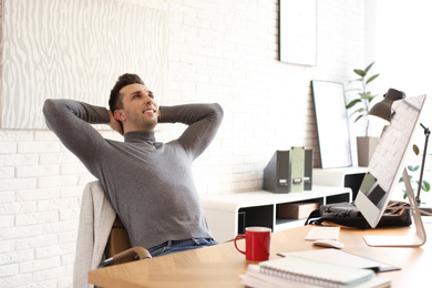 Young man relaxing at table in office during break