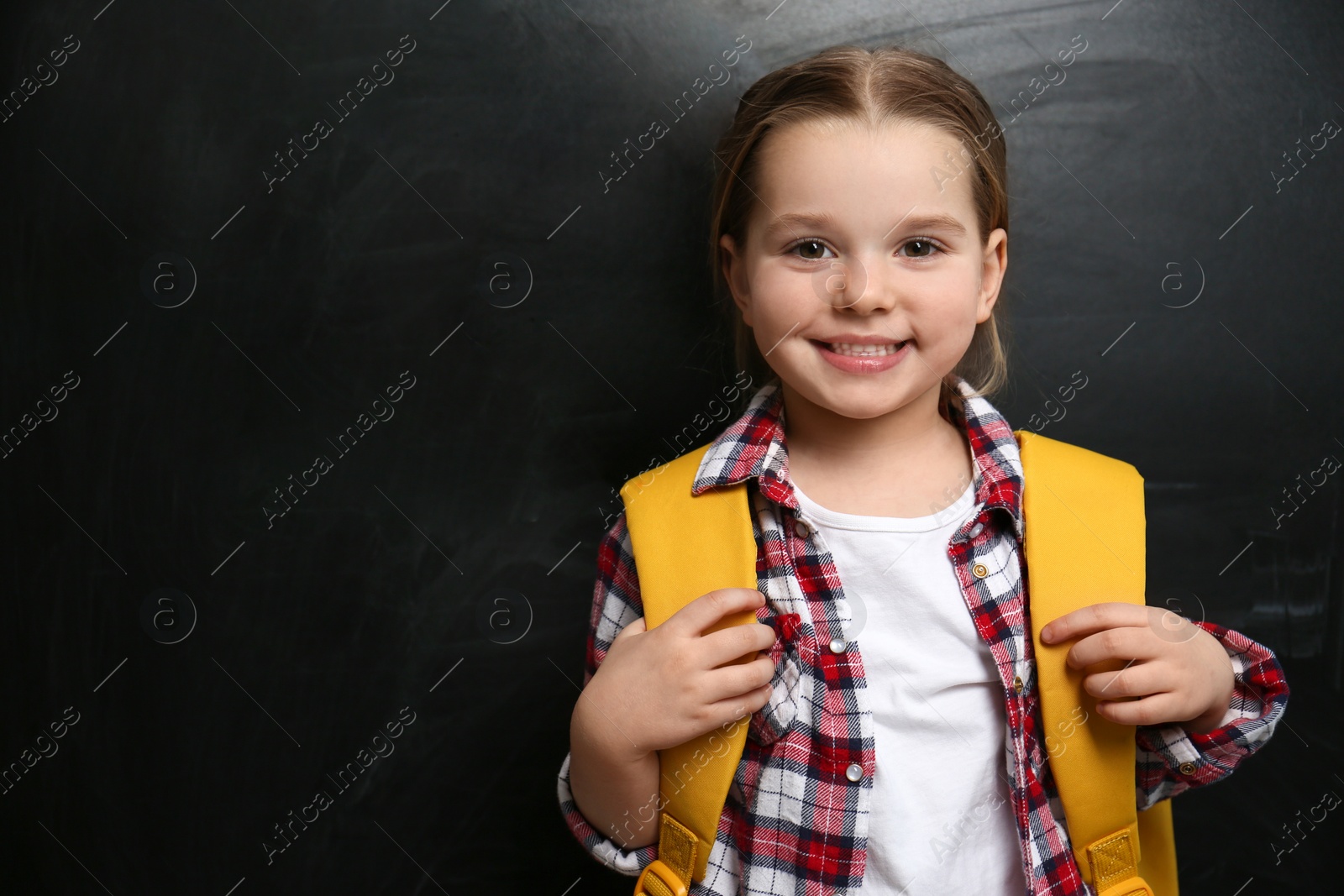 Photo of Cute little child near chalkboard, space for text. First time at school