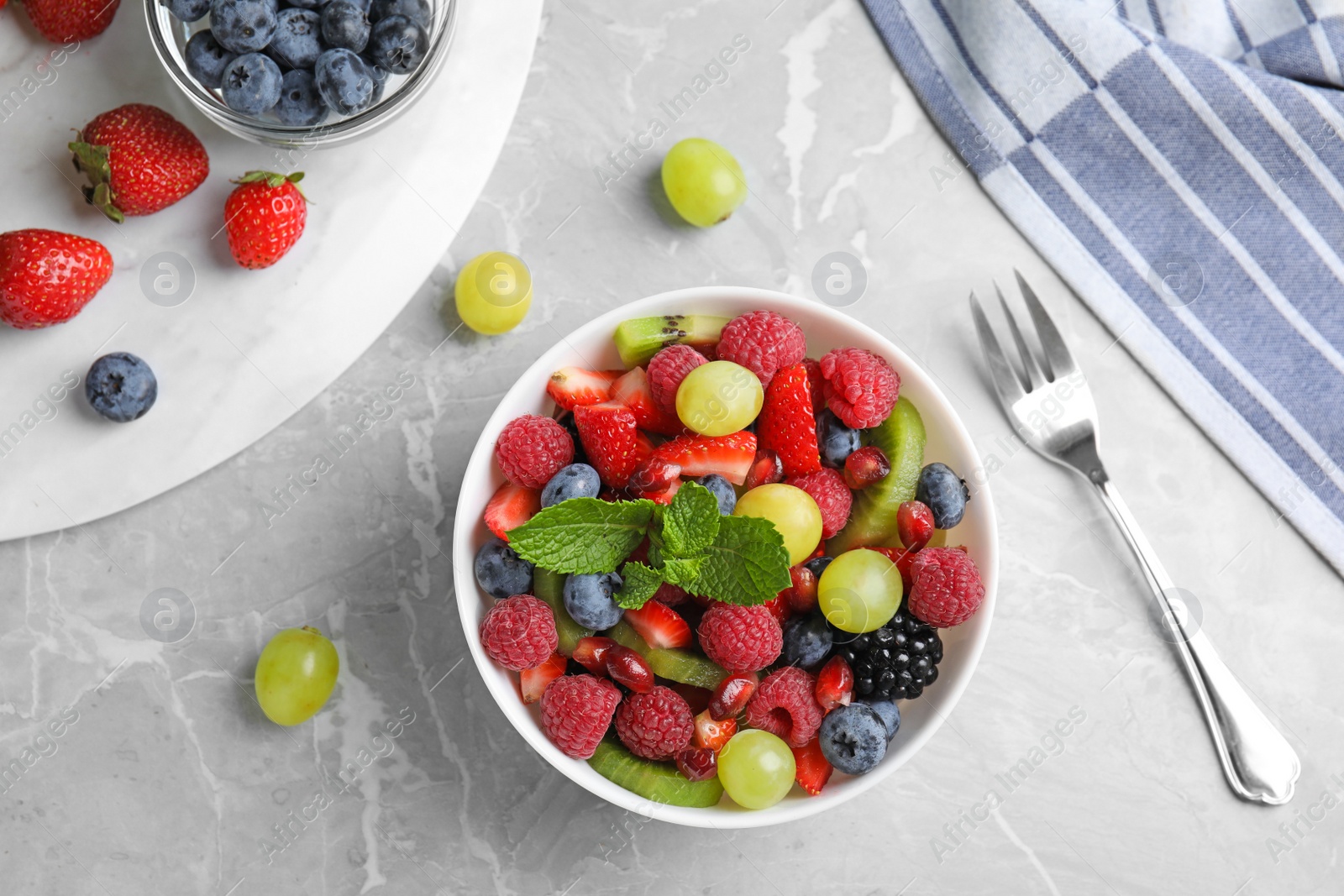 Photo of Fresh tasty fruit salad on grey marble table, flat lay