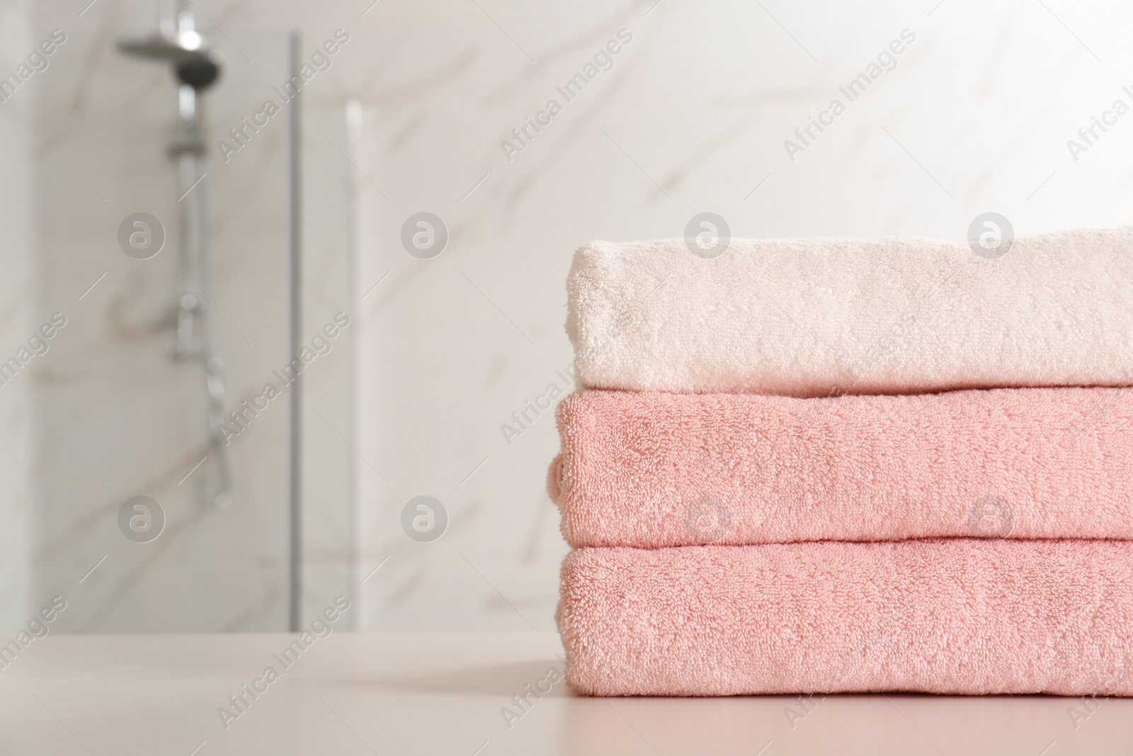 Photo of Stack of clean towels on table in bathroom, closeup. Space for text