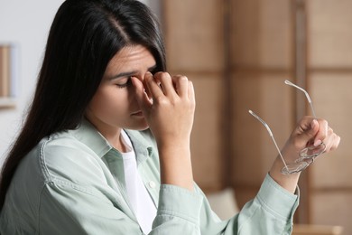 Photo of Young woman suffering from eyestrain in office