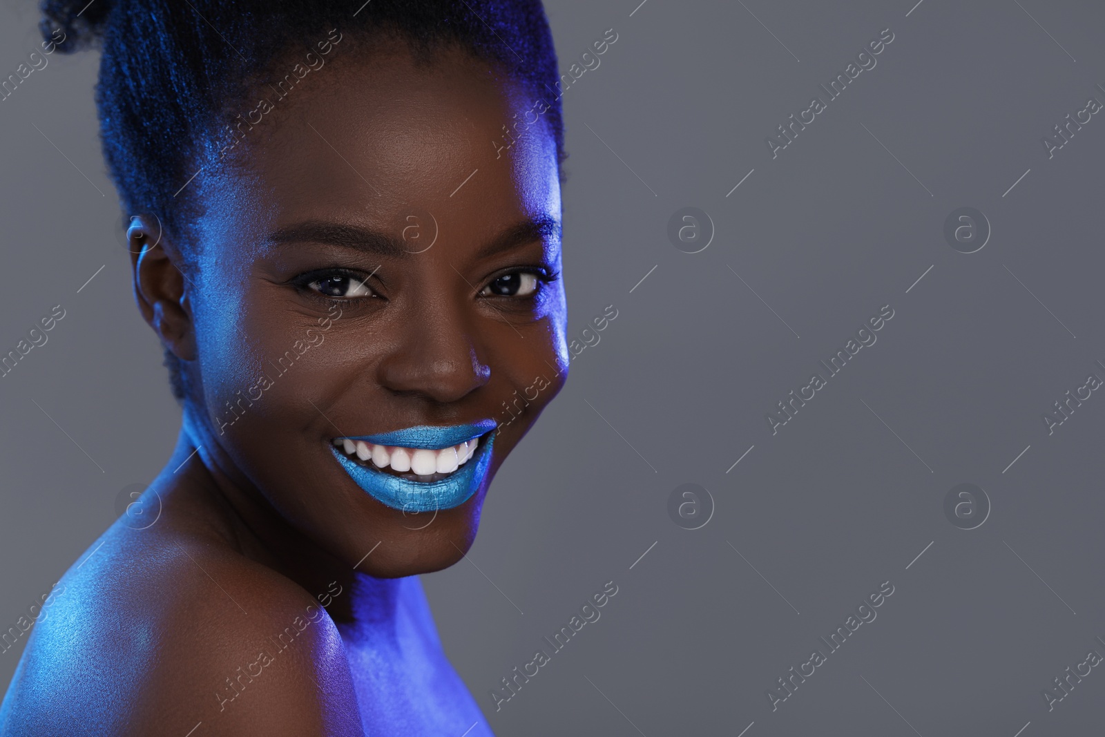 Photo of Fashionable portrait of beautiful happy woman with bright makeup on grey background, closeup. Space for text