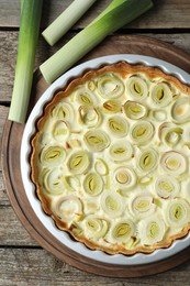 Photo of Tasty leek pie and raw stems on old wooden table, flat lay