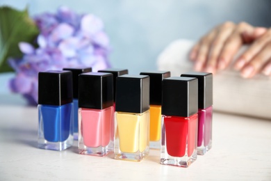 Photo of Bottles of bright nail polish and blurred woman on background