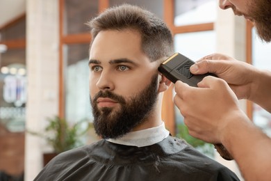 Photo of Professional hairdresser working with client in barbershop, closeup