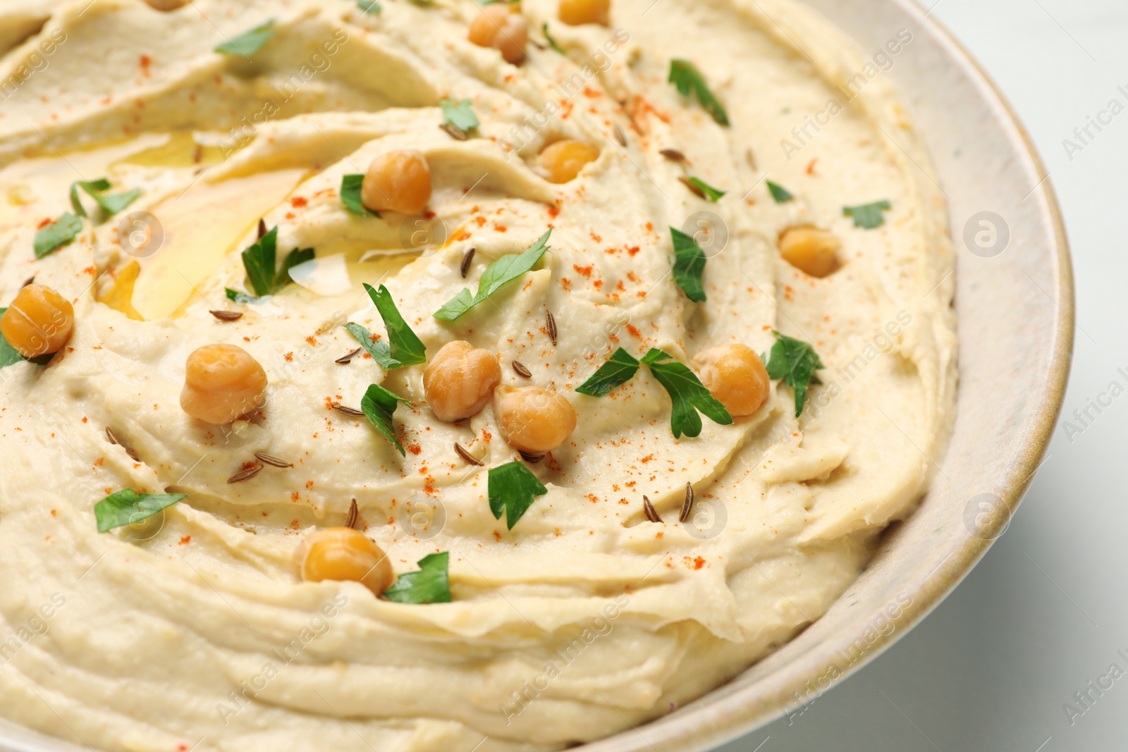 Photo of Tasty hummus with garnish in bowl, closeup