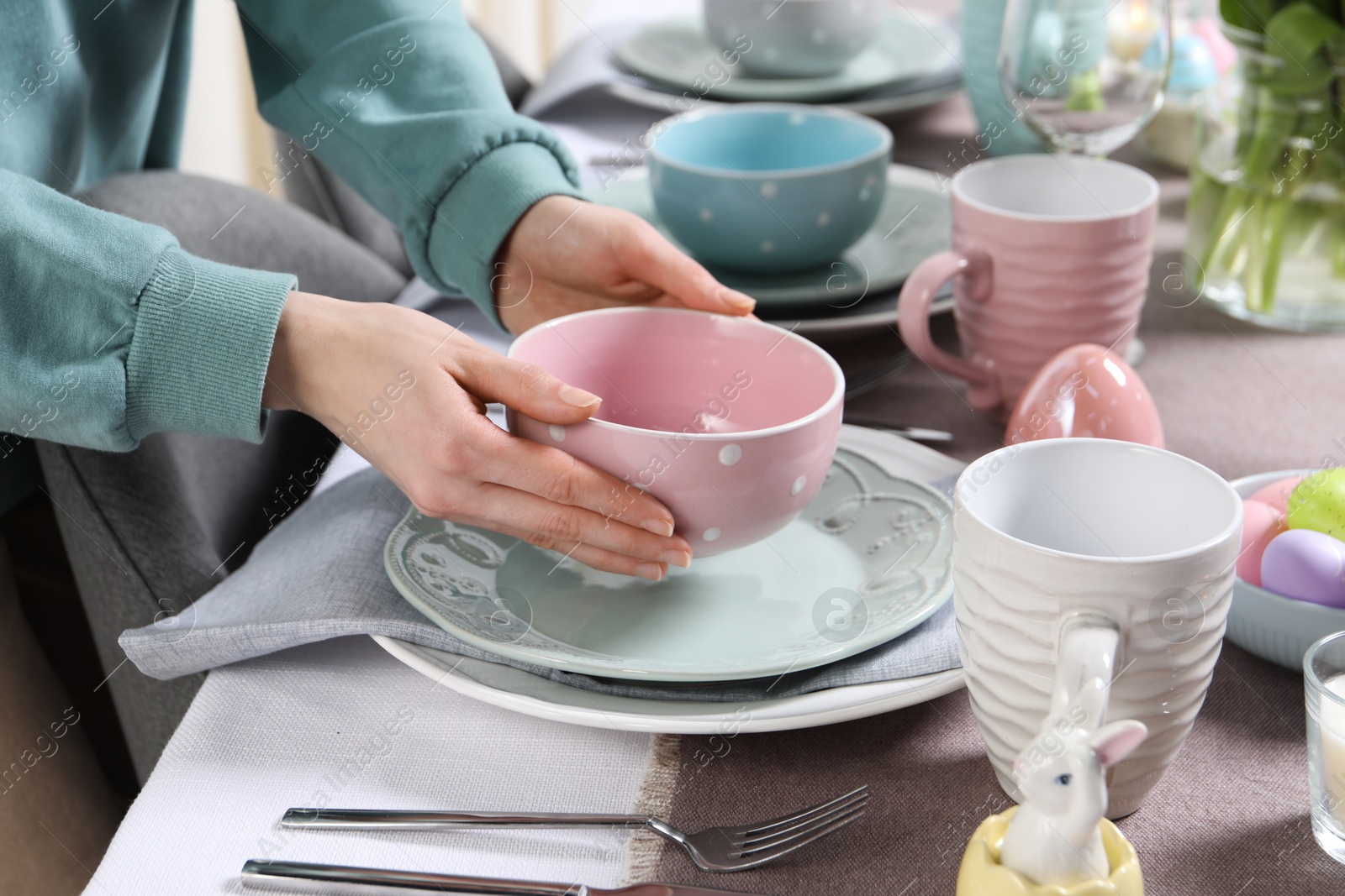 Photo of Woman setting table for festive Easter dinner at home, closeup