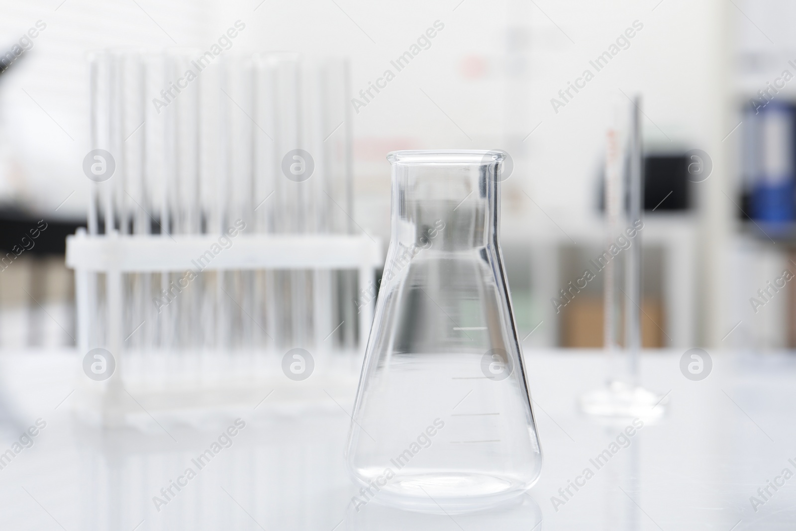 Photo of Laboratory analysis. Flask and test tubes on white table indoors, closeup