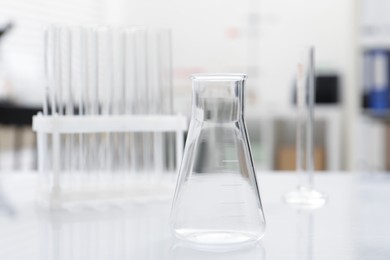 Photo of Laboratory analysis. Flask and test tubes on white table indoors, closeup