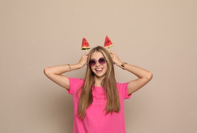 Beautiful girl with pieces of watermelon on beige background