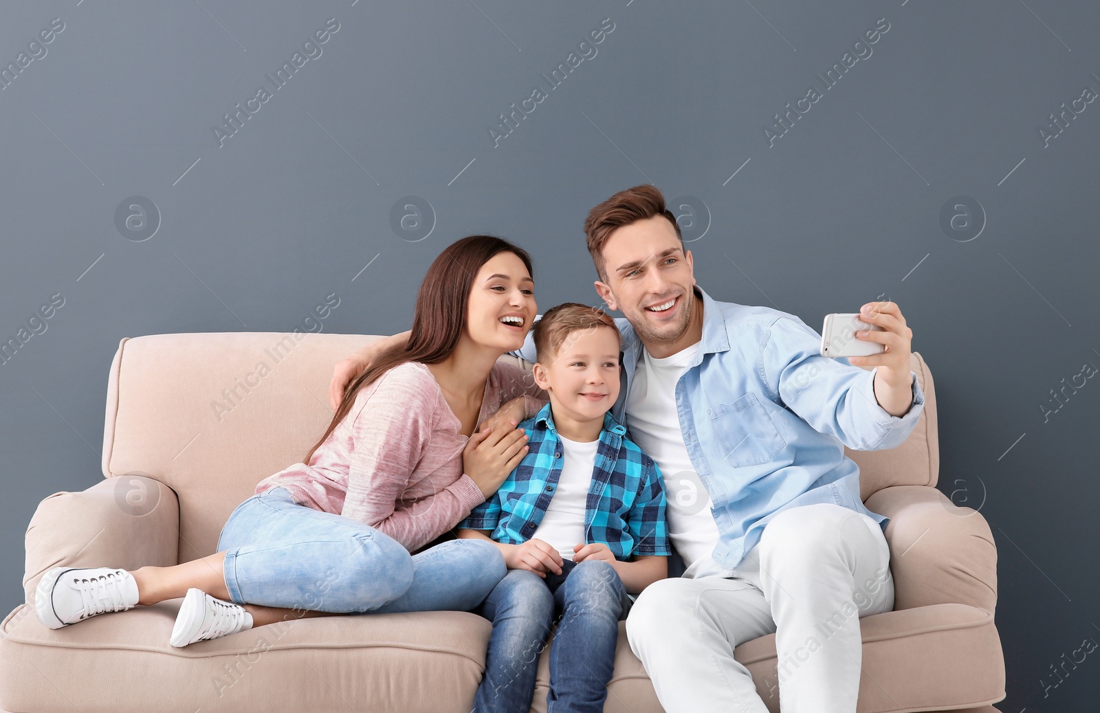 Photo of Happy family taking selfie on sofa, indoors