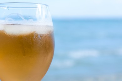 Photo of Cold beer in glass on beach, closeup. Space for text