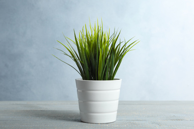 Photo of Artificial plant in flower pot on light grey wooden table