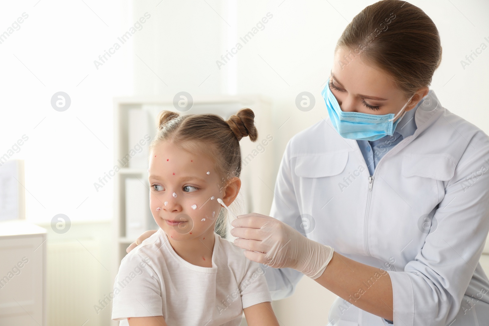 Photo of Doctor applying cream onto skin of little girl with chickenpox in clinic. Varicella zoster virus