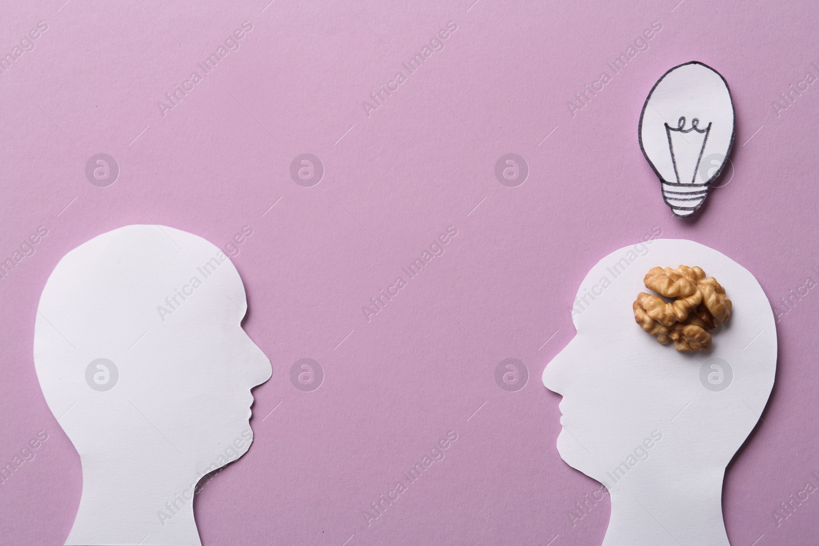 Photo of Flat lay composition with paper silhouettes of people and walnut on pink background