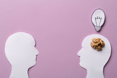 Flat lay composition with paper silhouettes of people and walnut on pink background