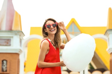 Photo of Happy young woman with cotton candy in amusement park