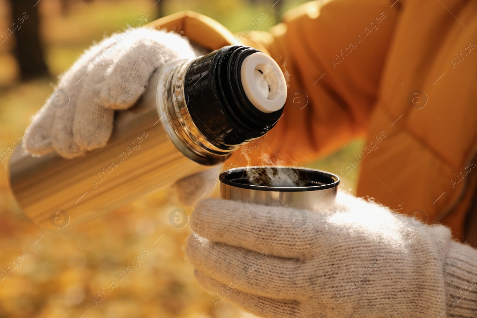 Photo of Woman pouring drink from thermos into cap outdoors, closeup