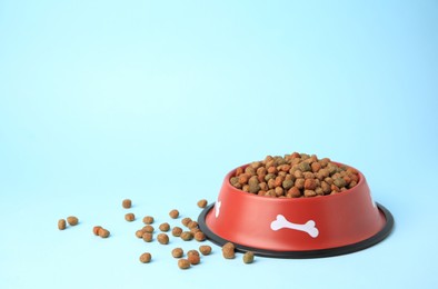 Dry dog food and feeding bowl on light blue background. Space for text