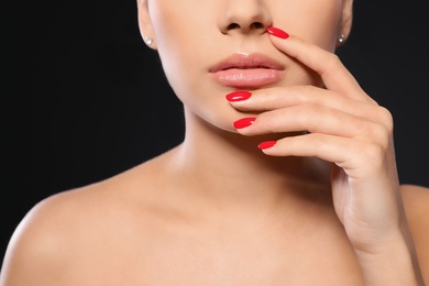 Photo of Beautiful young woman with bright manicure on black background, closeup. Nail polish trends