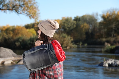 Female camper with sleeping bag near pond. Space for text