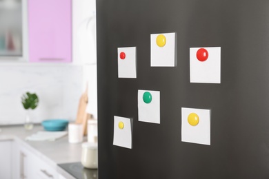 Blank paper notes and magnets on refrigerator door in kitchen