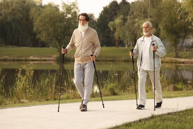 Two senior friends performing Nordic walking outdoors