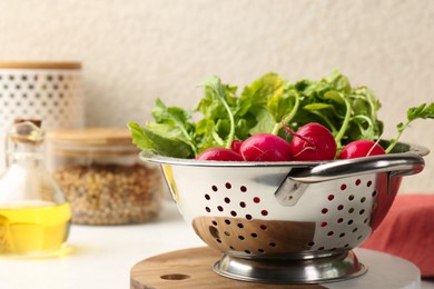 Photo of Wet radish in colander on white table, closeup