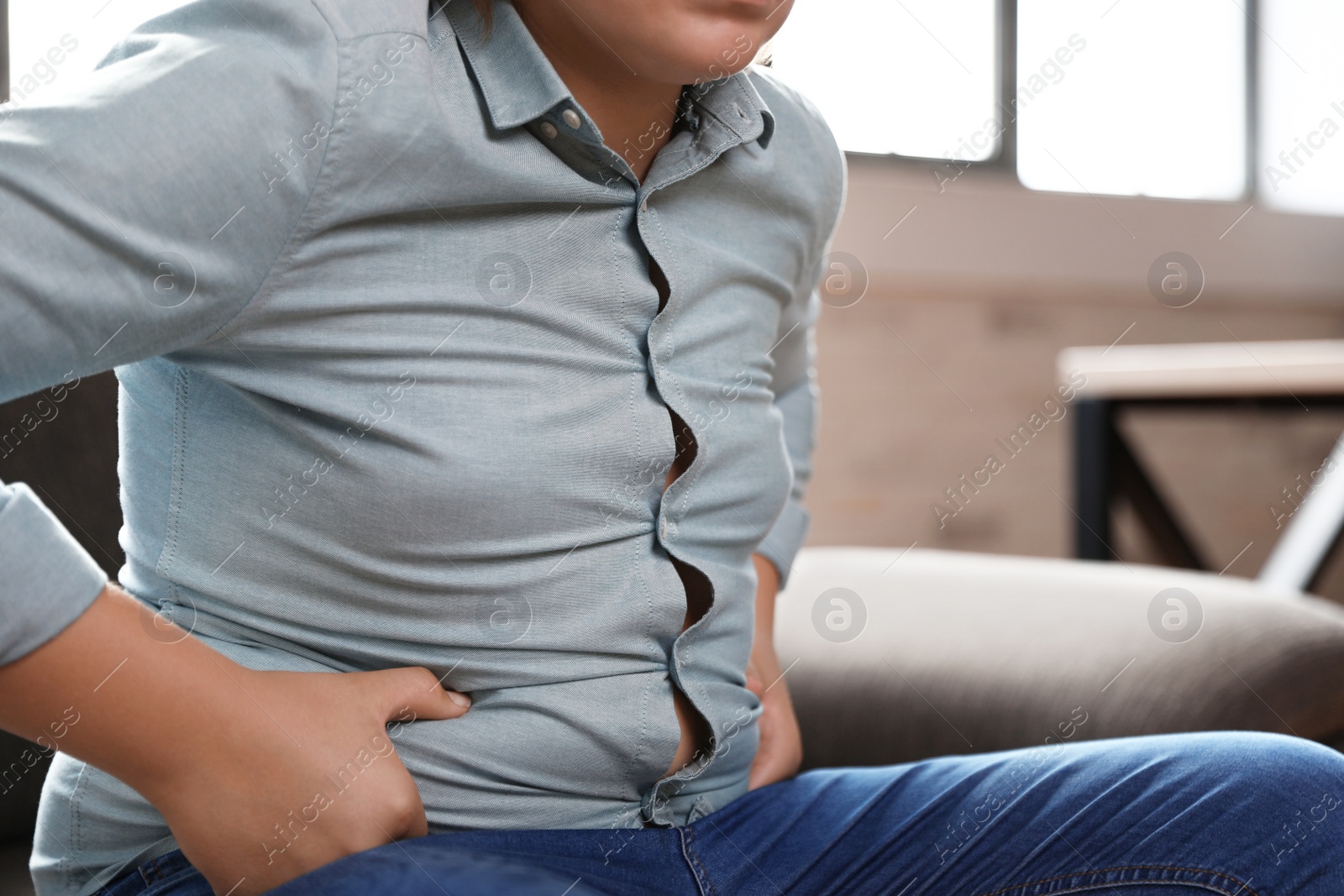 Photo of Overweight boy sitting on sofa at home, closeup view