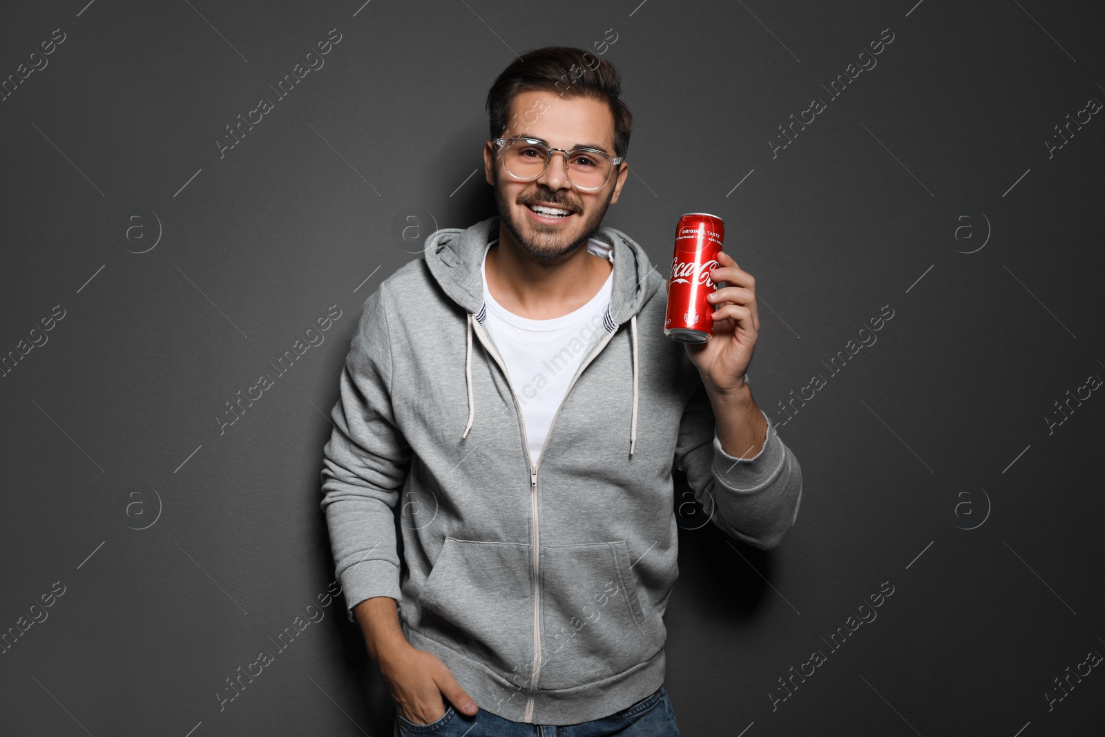 Photo of MYKOLAIV, UKRAINE - NOVEMBER 28, 2018: Young man with Coca-Cola can on dark background