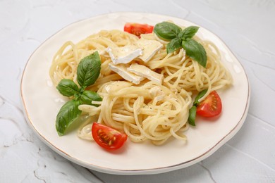 Photo of Delicious pasta with brie cheese, tomatoes and basil leaves on white textured table, closeup