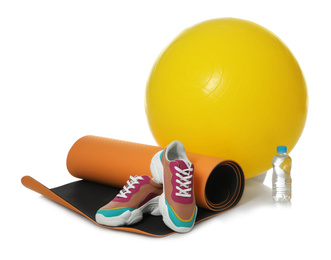 Photo of Fitness ball, yoga mat, bottle of water and sneakers isolated on white