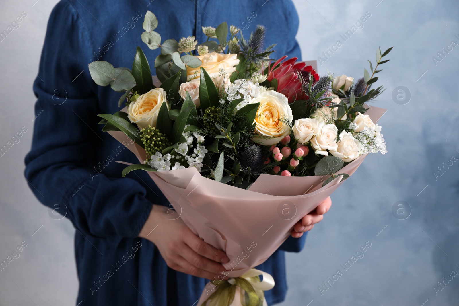 Photo of Woman with bouquet of beautiful roses on light blue background, closeup